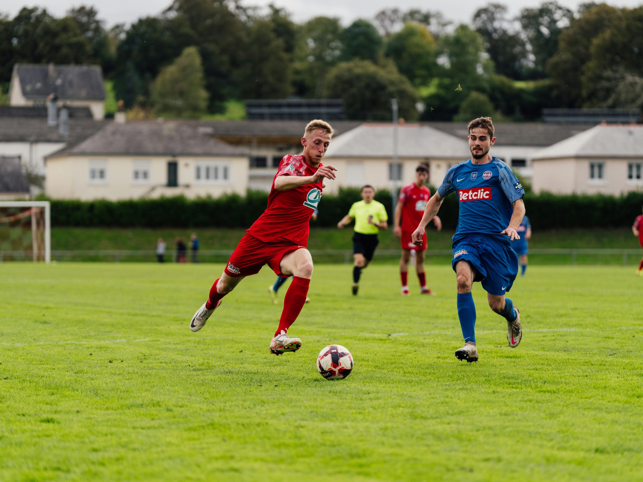 Action shot of soccer players competing on a lush green field outdoors.